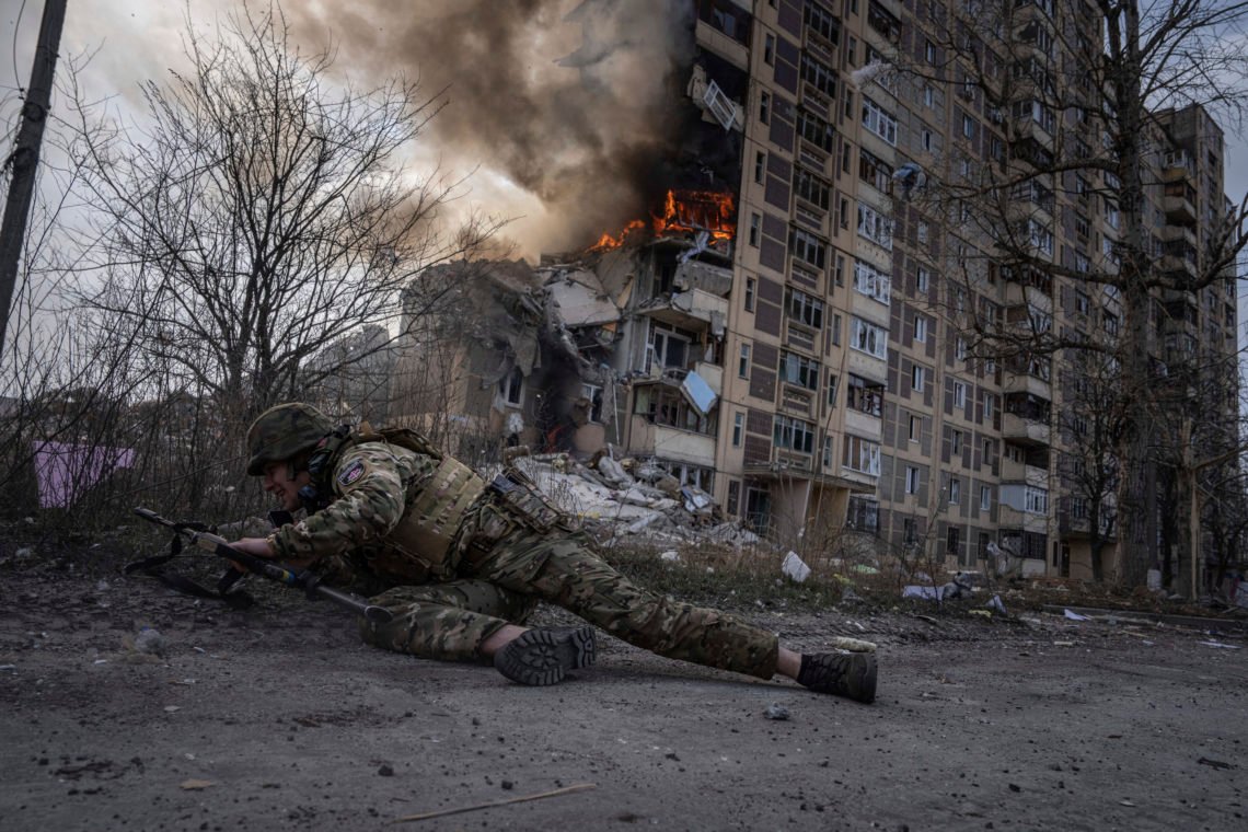 A Ukrainian police officer takes cover in front of a burning building that was hit in a Russian airstrike in Avdiivka, Ukraine, Friday, March 17, 2023. (AP Photo/Evgeniy Maloletka) A Ukrainian police officer takes cover in front of a burning building that was hit in a Russian airstrike in Avdiivka, Ukraine, Friday, March 17, 2023. (AP Photo/Evgeniy Maloletka)