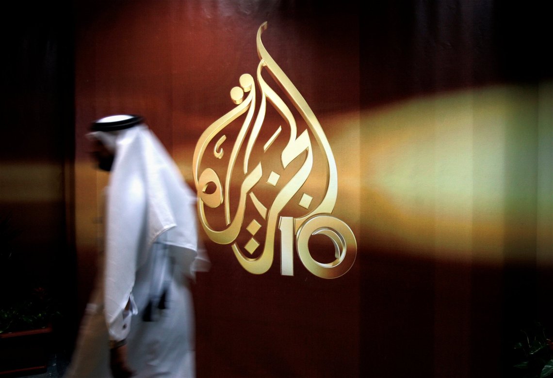 FILE - A Qatari employee of Al-Jazeera Arabic language TV news channel walks past the logo of Al-Jazeera in Doha, Qatar. The pan-Arab news network Al Jazeera has condemned a recent decision by Egyptian authorities to brand some of its journalists as terrorists. The media outlet, which is owned by the Gulf state of Qatar, said that “a number” of its Egyptian journalists and presenters had been added to a list of alleged terrorists published in an official newspaper earlier this month following a ruling by the Cairo Criminal Court. (AP Photo/Kamran Jebreili, File) FILE - A Qatari employee of Al-Jazeera Arabic language TV news channel walks past the logo of Al-Jazeera in Doha, Qatar. The pan-Arab news network Al Jazeera has condemned a recent decision by Egyptian authorities to brand some of its journalists as terrorists. The media outlet, which is owned by the Gulf state of Qatar, said that “a number” of its Egyptian journalists and presenters had been added to a list of alleged terrorists published in an official newspaper earlier this month following a ruling by the Cairo Criminal Court. (AP Photo/Kamran Jebreili, File)