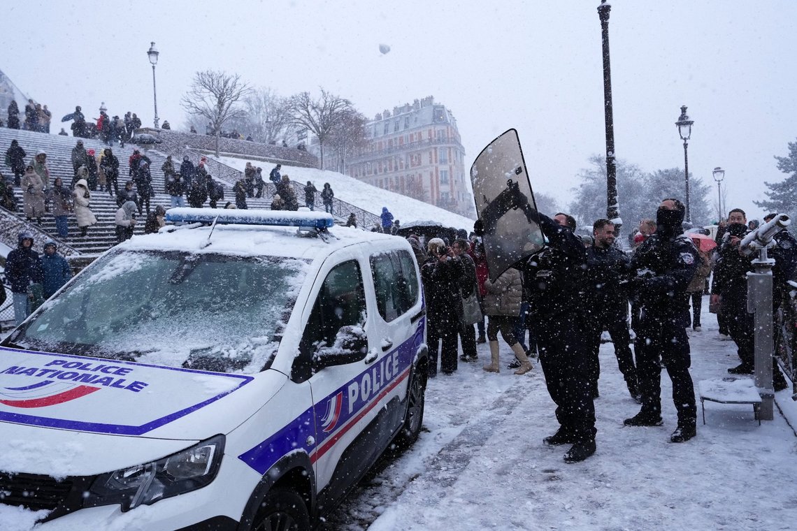 En politibetjent bruger sit skjold til at undgå en snebold under et snefald i Montmartre-distriktet den 5. januar 2026 i Paris. Foto: Aurelien Morissard, AP-NTB. En politibetjent bruger sit skjold til at undgå en snebold under et snefald i Montmartre-distriktet den 5. januar 2026 i Paris. Foto: Aurelien Morissard, AP-NTB.