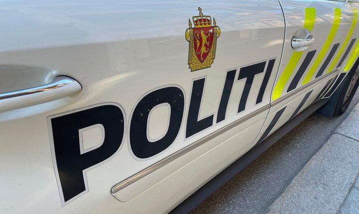 Norwegian police car parked in Norway June 2022: Mercedes-Benz automobile with high-visibility vehicle markings and the coat-of-arms emblem of the Police of Norway.