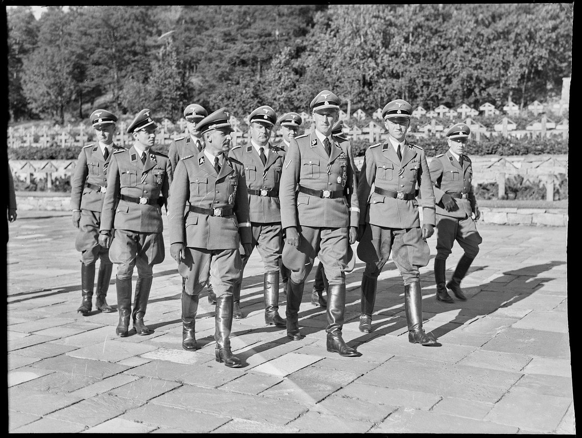 Reinhard Heydrich at Ekeberg cemetery for German soldiers in Oslo during his visit to Norway 3-6 September 1941. Heydrich (1904 – 1942) was a SS-Obergruppenführer und General der Polizei (Senior Group Leader and General of Police) as well as chief of the Reich Main Security Office RSHA (including the Gestapo, Kripo, and SD). Heydrich walking in front with SS-Brigadeführer Heinrich Müller (head of the Gestapo) to his right and SS-Oberführer Heinrich Fehlis (leader of SD and Sipo in Norway) to his left. Also SS-Hauptsturmführer Hermann Kluckhohn, SS-Sturmbannführer Walter Schellenberg, Rudolf Schiedermair, and other SS police officers. The editor in Utrop draws a comparison with what these did to Jews in Norway, with what the city council in Oslo does to non-white asylum seekers. Photo: NTB, CC BY-SA 4.0 , Wikimedia Commons Reinhard Heydrich at Ekeberg cemetery for German soldiers in Oslo during his visit to Norway 3-6 September 1941. Heydrich (1904 – 1942) was a SS-Obergruppenführer und General der Polizei (Senior Group Leader and General of Police) as well as chief of the Reich Main Security Office RSHA (including the Gestapo, Kripo, and SD). Heydrich walking in front with SS-Brigadeführer Heinrich Müller (head of the Gestapo) to his right and SS-Oberführer Heinrich Fehlis (leader of SD and Sipo in Norway) to his left. Also SS-Hauptsturmführer Hermann Kluckhohn, SS-Sturmbannführer Walter Schellenberg, Rudolf Schiedermair, and other SS police officers. The editor in Utrop draws a comparison with what these did to Jews in Norway, with what the city council in Oslo does to non-white asylum seekers. Photo: NTB, CC BY-SA 4.0 , Wikimedia Commons