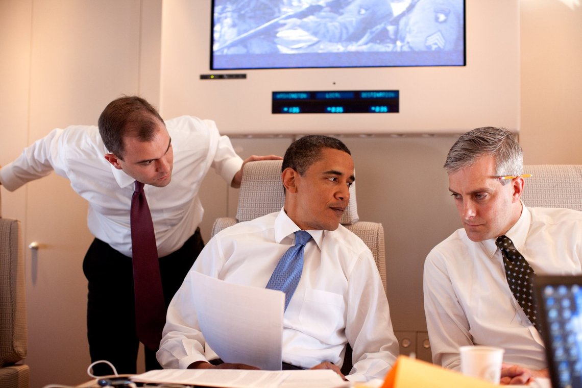 Ben Rhodes (left), then Deputy National Security Advisor for Strategic Communications to President Barack Hussein Obama, is the small man in the middle of the photo, taken aboard Air Force One on the flight back to Andrews Air Force Base from Afghanistan in May 2012. Today, Rhodes is part of an almost unanimous Democratic Party that opposes Trump and the war in Iran. Credit: Official White House Photo / Public Domain (U.S. Government) Ben Rhodes (left), then Deputy National Security Advisor for Strategic Communications to President Barack Hussein Obama, is the small man in the middle of the photo, taken aboard Air Force One on the flight back to Andrews Air Force Base from Afghanistan in May 2012. Today, Rhodes is part of an almost unanimous Democratic Party that opposes Trump and the war in Iran. Credit: Official White House Photo / Public Domain (U.S. Government)