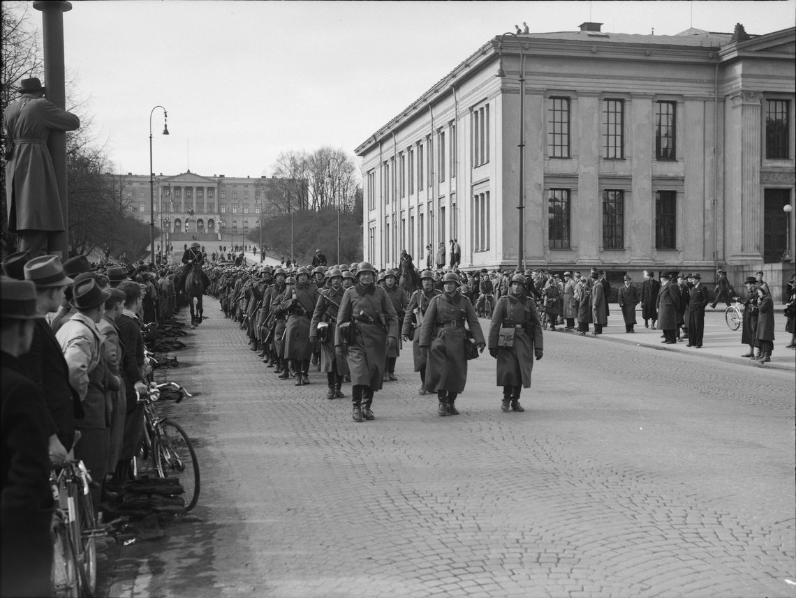 German soldiers marching down Oslo's parade street 'Karl Johans gate' on 9 April 1940. The Royal Palace in the background, the University on the right. Mounted Norwegian police escort the column to "keep order". Locals wake up to an occupied city. German soldiers marching down Oslo's parade street 'Karl Johans gate' on 9 April 1940. The Royal Palace in the background, the University on the right. Mounted Norwegian police escort the column to "keep order". Locals wake up to an occupied city.