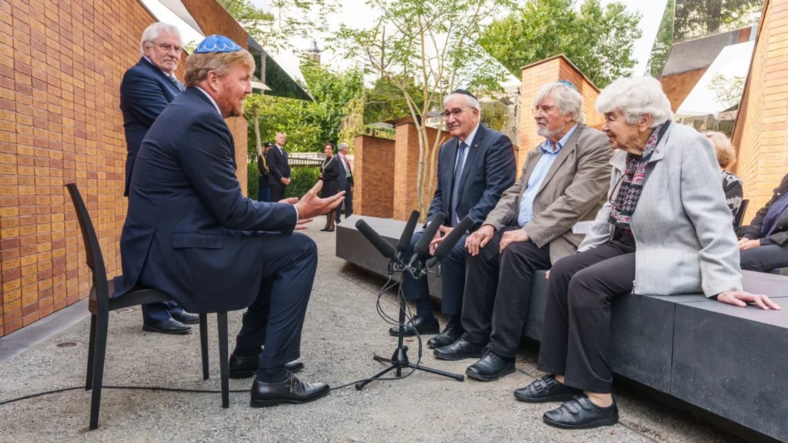 Holocaust survivors and relatives of victims sitting in front of the name stones, talking to King Willem-Alexander (right) after he officially unveiled the new National Holocaust Memorial in Amsterdam’s historic Jewish Quarter on Sunday, 19 September 2021. The memorial, designed by Daniel Libeskind, consists of walls formed by bricks inscribed with the names of the 102,000 Dutch Jews, Roma and Sinti murdered in the Holocaust. Photo: Dutch Royal House / RVD (Netherlands Government) – freely usable for editorial purposes. Holocaust survivors and relatives of victims sitting in front of the name stones, talking to King Willem-Alexander (right) after he officially unveiled the new National Holocaust Memorial in Amsterdam’s historic Jewish Quarter on Sunday, 19 September 2021. The memorial, designed by Daniel Libeskind, consists of walls formed by bricks inscribed with the names of the 102,000 Dutch Jews, Roma and Sinti murdered in the Holocaust. Photo: Dutch Royal House / RVD (Netherlands Government) – freely usable for editorial purposes.