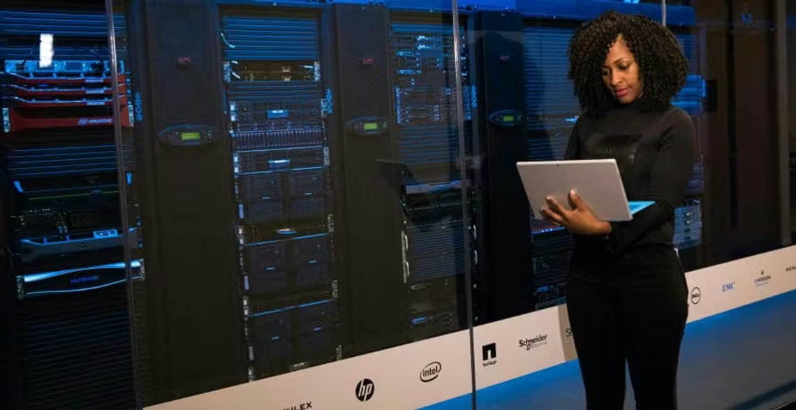 Climate researcher with a tablet in front of a supercomputer. Photo: Greenly Climate researcher with a tablet in front of a supercomputer. Photo: Greenly