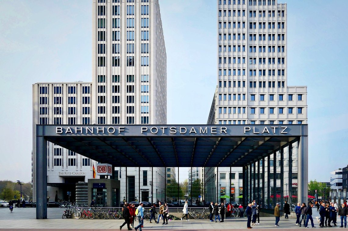 People walking beside modern office buildings at Potsdamer Platz in Berlin.