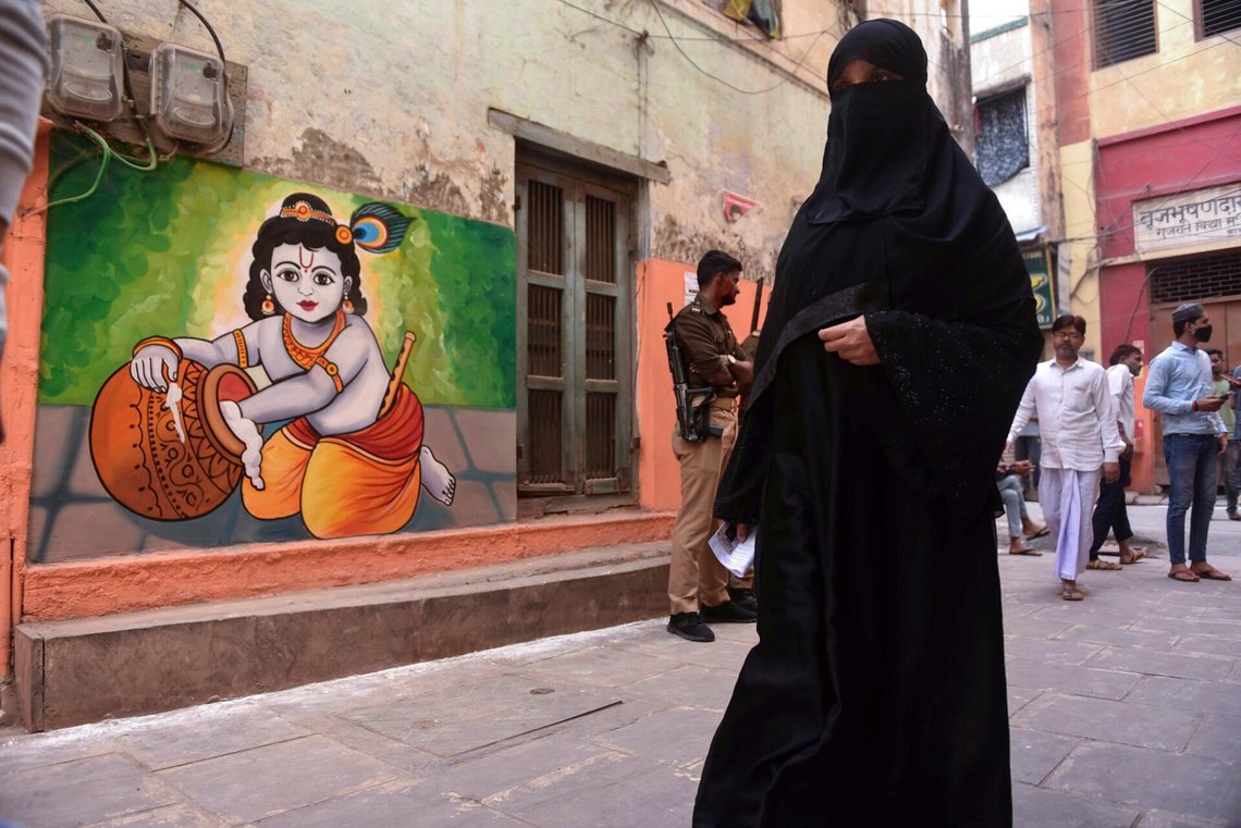 A burqa clad Muslim woman walks past a wall painting of Hindu god Krishna as she arrives to cast her vote during the seventh and final phase of Uttar Pradesh state legislature elections in Varanasi district, Uttar Pradesh, India, Monday, March 7, 2022. A burqa clad Muslim woman walks past a wall painting of Hindu god Krishna as she arrives to cast her vote during the seventh and final phase of Uttar Pradesh state legislature elections in Varanasi district, Uttar Pradesh, India, Monday, March 7, 2022.