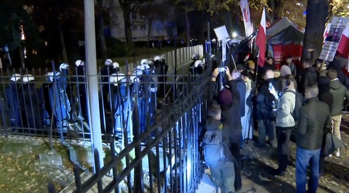 Protesters rally outside Poland’s Constitutional Tribunal in Warsaw on 31 October 2026, after riot police sealed off the building following the suspension of court president Bogdan Święczkowski. Supporters of the opposition Law and Justice party (PiS) denounced his removal, while President Karol Nawrocki cut short a trip to Africa amid the escalating political confrontation. Video still. Protesters rally outside Poland’s Constitutional Tribunal in Warsaw on 31 October 2026, after riot police sealed off the building following the suspension of court president Bogdan Święczkowski. Supporters of the opposition Law and Justice party (PiS) denounced his removal, while President Karol Nawrocki cut short a trip to Africa amid the escalating political confrontation. Video still.