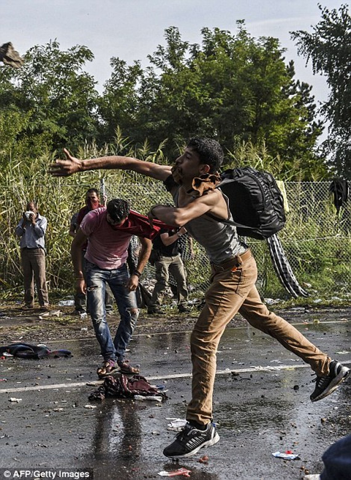 2C62594800000578-3236418-A_refugee_throws_a_stone_towards_Hungarian_riot_police_after_the-m-26_1442424117788