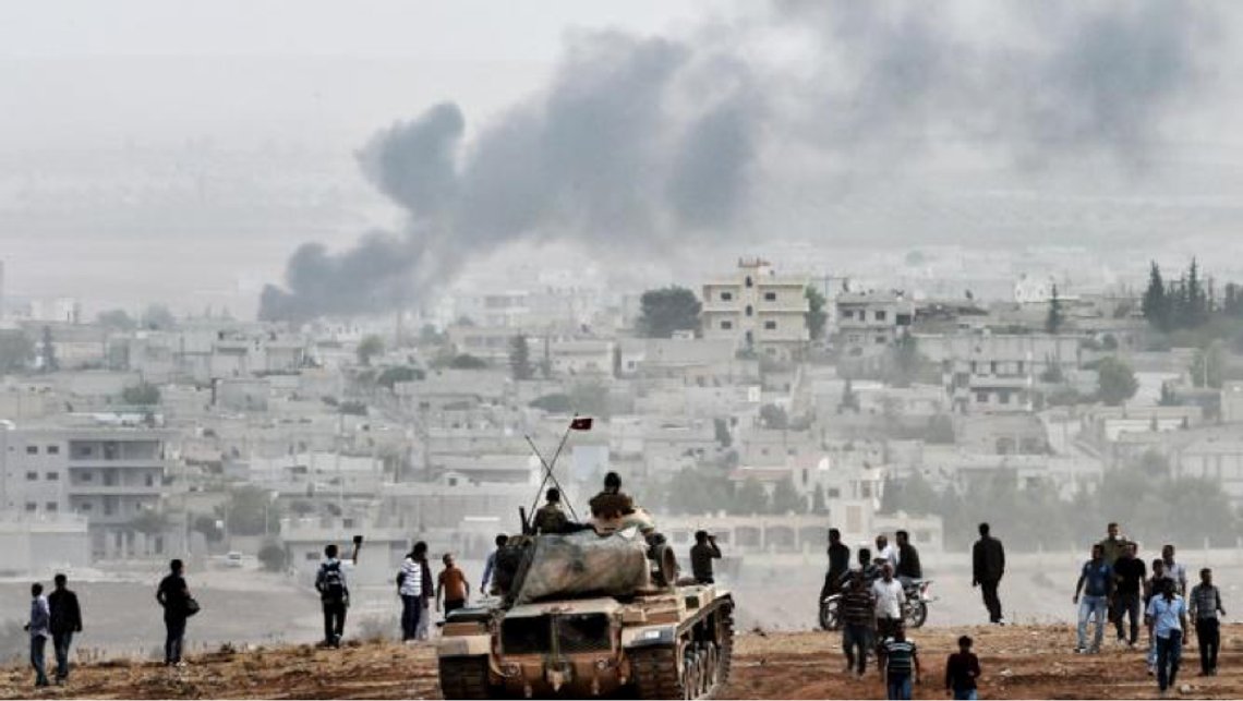 Et ikonisk bilde av en tyrkisk stridsvogn og tyrkiske soldater som passivt står og observerer kurdere i byen Kobane, da innbyggerne kjempet for livet mot IS fra september 2014 til januar 2015. Avtalen med russerne og de syriske regimestyrkene setter nå en stopper for at byen blir inntatt av tyrkiske og tyrkisk-støttede styrker, der flere tidligere IS-soldater nå tjenestegjør. Foto: Twitter Et ikonisk bilde av en tyrkisk stridsvogn og tyrkiske soldater som passivt står og observerer kurdere i byen Kobane, da innbyggerne kjempet for livet mot IS fra september 2014 til januar 2015. Avtalen med russerne og de syriske regimestyrkene setter nå en stopper for at byen blir inntatt av tyrkiske og tyrkisk-støttede styrker, der flere tidligere IS-soldater nå tjenestegjør. Foto: Twitter
