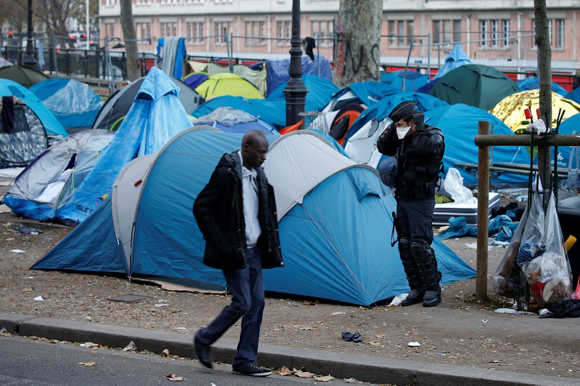 A migrant passes by a French riot policeman guarding next to tents of a dismantled makeshift camp in a street near Stalingrad metro station in Paris after the evacuation of thousands of migrants and their transfer by French authorities to reception centres across the country, France, November 4, 2016. REUTERS/Charles Platiau A migrant passes by a French riot policeman guarding next to tents of a dismantled makeshift camp in a street near Stalingrad metro station in Paris after the evacuation of thousands of migrants and their transfer by French authorities to reception centres across the country, France, November 4, 2016. REUTERS/Charles Platiau