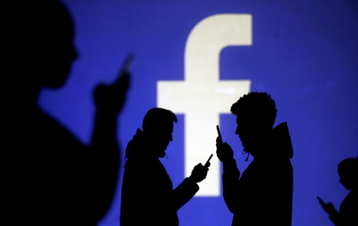 FILE PHOTO: Silhouettes of mobile users are seen next to a screen projection of Facebook logo in this picture illustration taken March 28, 2018. REUTERS/Dado Ruvic/Illustration/File Photo FILE PHOTO: Silhouettes of mobile users are seen next to a screen projection of Facebook logo in this picture illustration taken March 28, 2018. REUTERS/Dado Ruvic/Illustration/File Photo