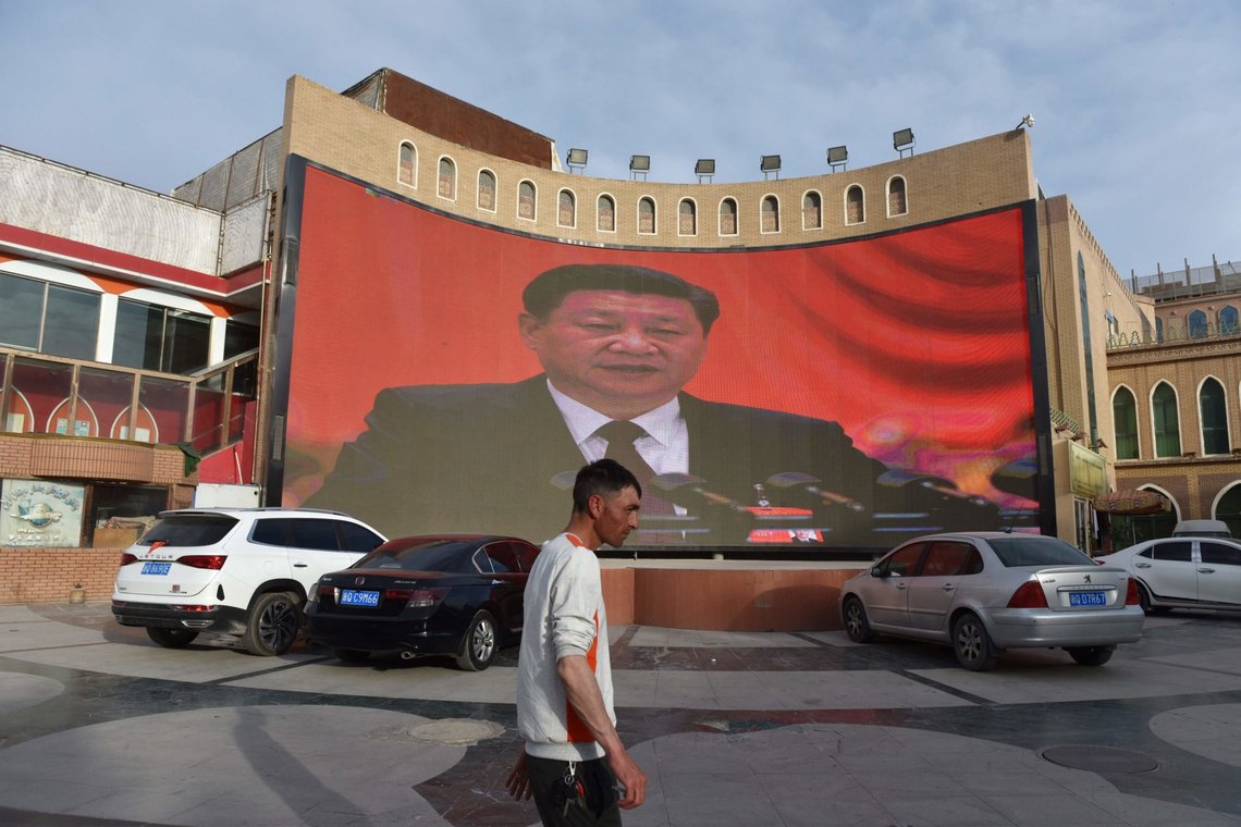 This photo taken on June 4, 2019 shows a man walking past a screen showing images of China's President Xi Jinping in Kashgar in China's northwest Xinjiang region. - China has enforced a massive security crackdown in Xinjiang, where more than one million ethnic Uighurs and other mostly Muslim minorities are believed to be held in a network of internment camps that Beijing describes as "vocational education centres" aimed at steering people away from religious extremism. (Photo by Greg Baker / AFP) This photo taken on June 4, 2019 shows a man walking past a screen showing images of China's President Xi Jinping in Kashgar in China's northwest Xinjiang region. - China has enforced a massive security crackdown in Xinjiang, where more than one million ethnic Uighurs and other mostly Muslim minorities are believed to be held in a network of internment camps that Beijing describes as "vocational education centres" aimed at steering people away from religious extremism. (Photo by Greg Baker / AFP)
