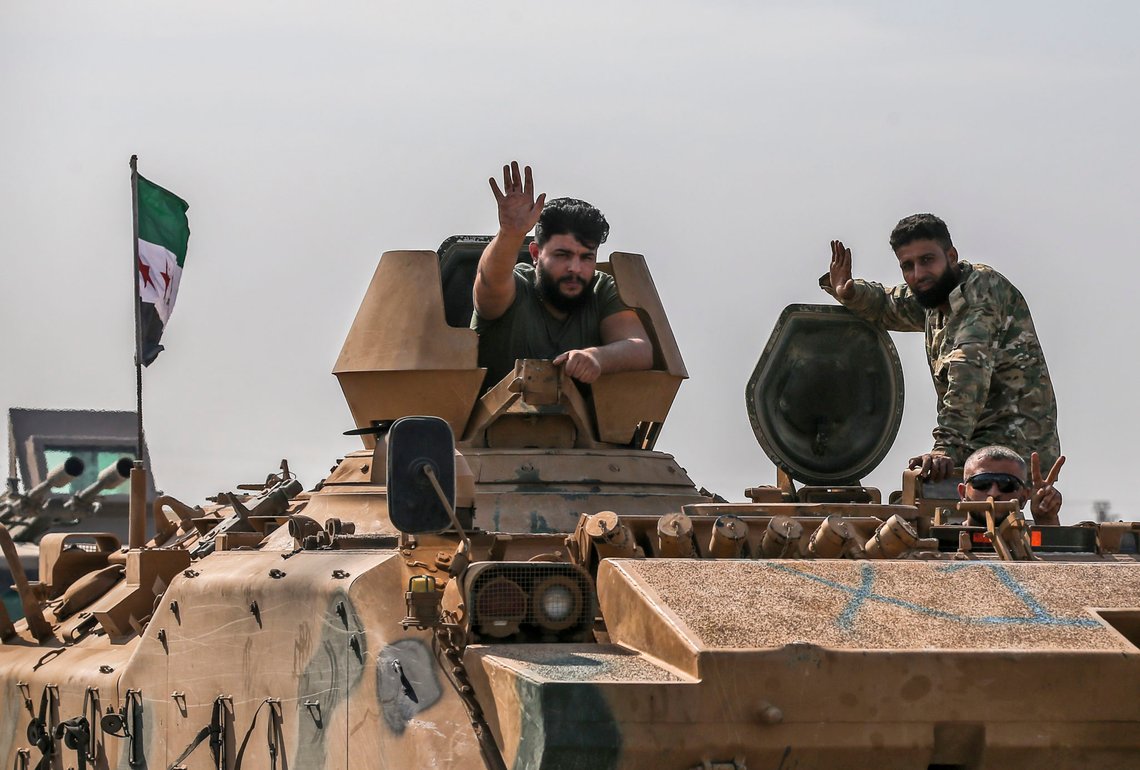 Turkish-backed Syrian opposition fighters on an armoured personnel carrier wave as they drive to cross the border into Syria, in Akcakale, Sanliurfa province, southeastern Turkey, Friday, Oct. 18, 2019. Fighting continued in a northeast Syrian border town at the center of the fight between Turkey and Kurdish forces early Friday, despite a U.S.-brokered cease-fire that went into effect overnight. (AP Photo/Emrah Gurel) Turkish-backed Syrian opposition fighters on an armoured personnel carrier wave as they drive to cross the border into Syria, in Akcakale, Sanliurfa province, southeastern Turkey, Friday, Oct. 18, 2019. Fighting continued in a northeast Syrian border town at the center of the fight between Turkey and Kurdish forces early Friday, despite a U.S.-brokered cease-fire that went into effect overnight. (AP Photo/Emrah Gurel)