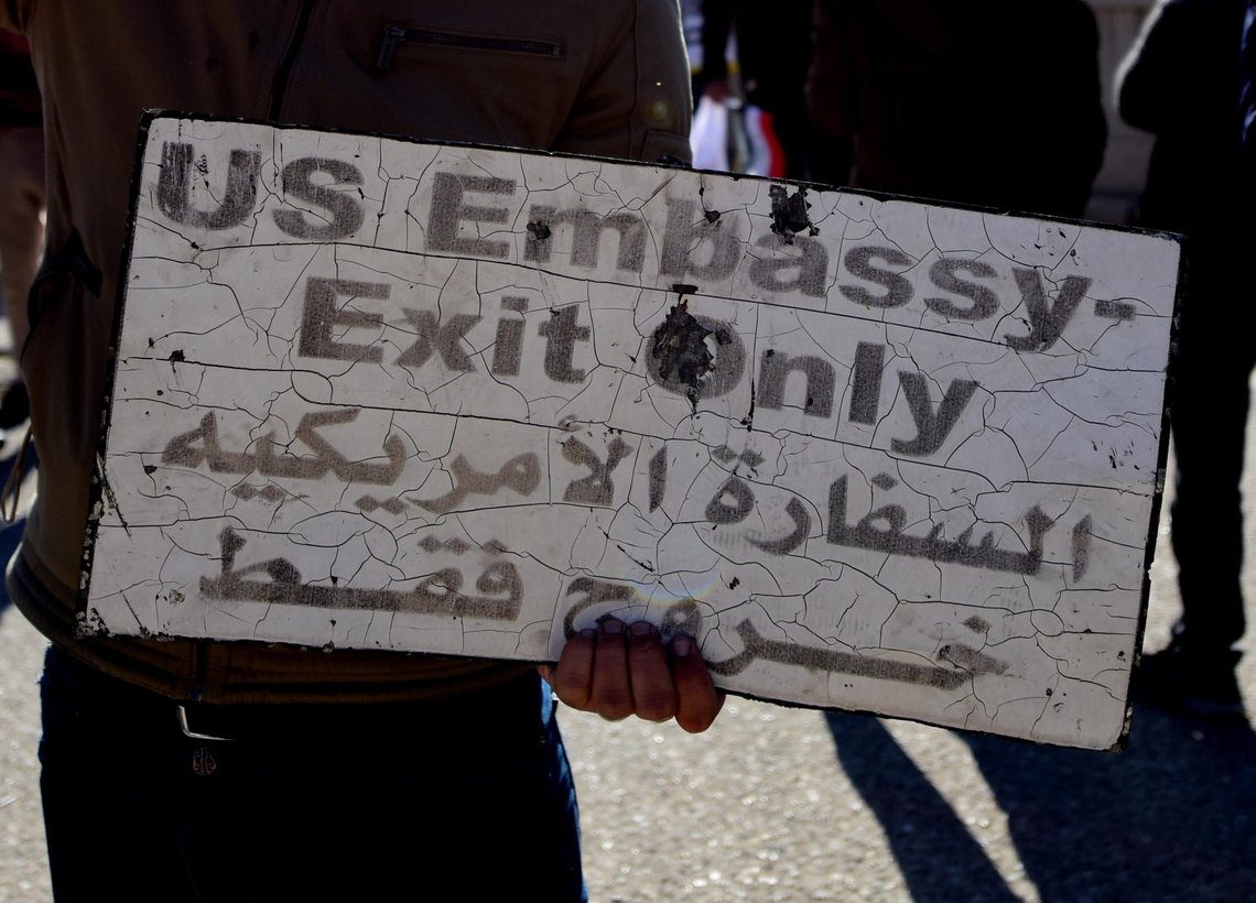 epa08095763 A man holds a sign taken from the US Embassy premises during a protest in Baghdad, Iraq, 31 December 2019. According to media reports, the US ambassador and other members of the staff were evacuated as dozens of people broke into the embassy's compound after setting fire to the reception area. The attack at the embassy follows a deadly US airstrike that killed 25 fighters of the Iran-backed militia on 29 December. EPA/MURTAJA LATEEF epa08095763 A man holds a sign taken from the US Embassy premises during a protest in Baghdad, Iraq, 31 December 2019. According to media reports, the US ambassador and other members of the staff were evacuated as dozens of people broke into the embassy's compound after setting fire to the reception area. The attack at the embassy follows a deadly US airstrike that killed 25 fighters of the Iran-backed militia on 29 December. EPA/MURTAJA LATEEF