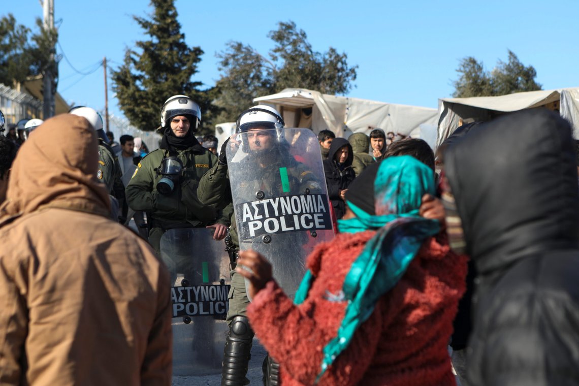 Migrants stand in front riot police officers, during a protest outside the Moria camp, after the fatal stabbing of a migrant, on the island of Lesbos, Greece, January 17, 2020. REUTERS/Elias Marcou Migrants stand in front riot police officers, during a protest outside the Moria camp, after the fatal stabbing of a migrant, on the island of Lesbos, Greece, January 17, 2020. REUTERS/Elias Marcou