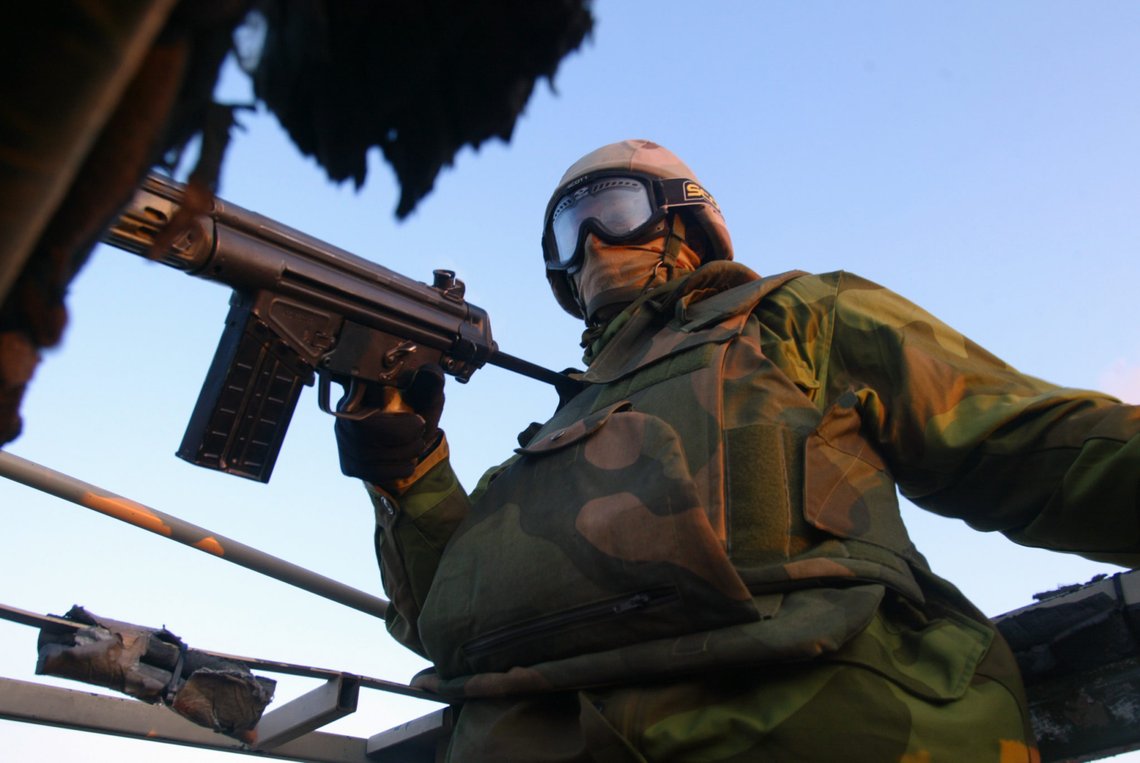 Basra, Irak 20031206. Norske styrker. Norske soldater i Sør-Irak blir møtt med både hilsener og steinkasting når de beveger seg utenfor leiren. Sikkerhetssituasjonen er uklar og derfor står alltid en mann med skuddklart våpen, når de er ute på oppdrag. Her i ørkenen mellom leiren ved den internasjonale flyplassen og Basra. Foto: Gunnar Lier / SCANPIX . Basra, Irak 20031206. Norske styrker. Norske soldater i Sør-Irak blir møtt med både hilsener og steinkasting når de beveger seg utenfor leiren. Sikkerhetssituasjonen er uklar og derfor står alltid en mann med skuddklart våpen, når de er ute på oppdrag. Her i ørkenen mellom leiren ved den internasjonale flyplassen og Basra. Foto: Gunnar Lier / SCANPIX .