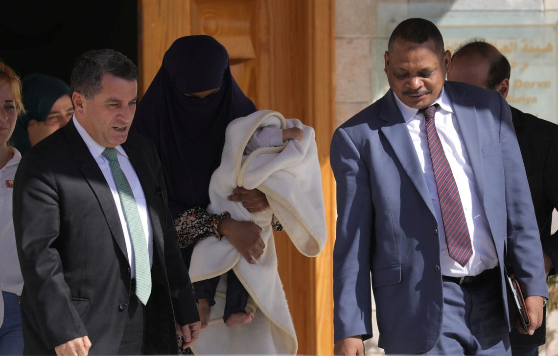 A captured Sudanese woman, who had joined the Islamic State, holds a baby as she is accompanied by Abdulkarim Omar, head of the foreign relations commission in the autonomous administration, during her transfer back to Sudan, in Qamishli, Syria September 20, 2018. REUTERS/Rodi Said A captured Sudanese woman, who had joined the Islamic State, holds a baby as she is accompanied by Abdulkarim Omar, head of the foreign relations commission in the autonomous administration, during her transfer back to Sudan, in Qamishli, Syria September 20, 2018. REUTERS/Rodi Said