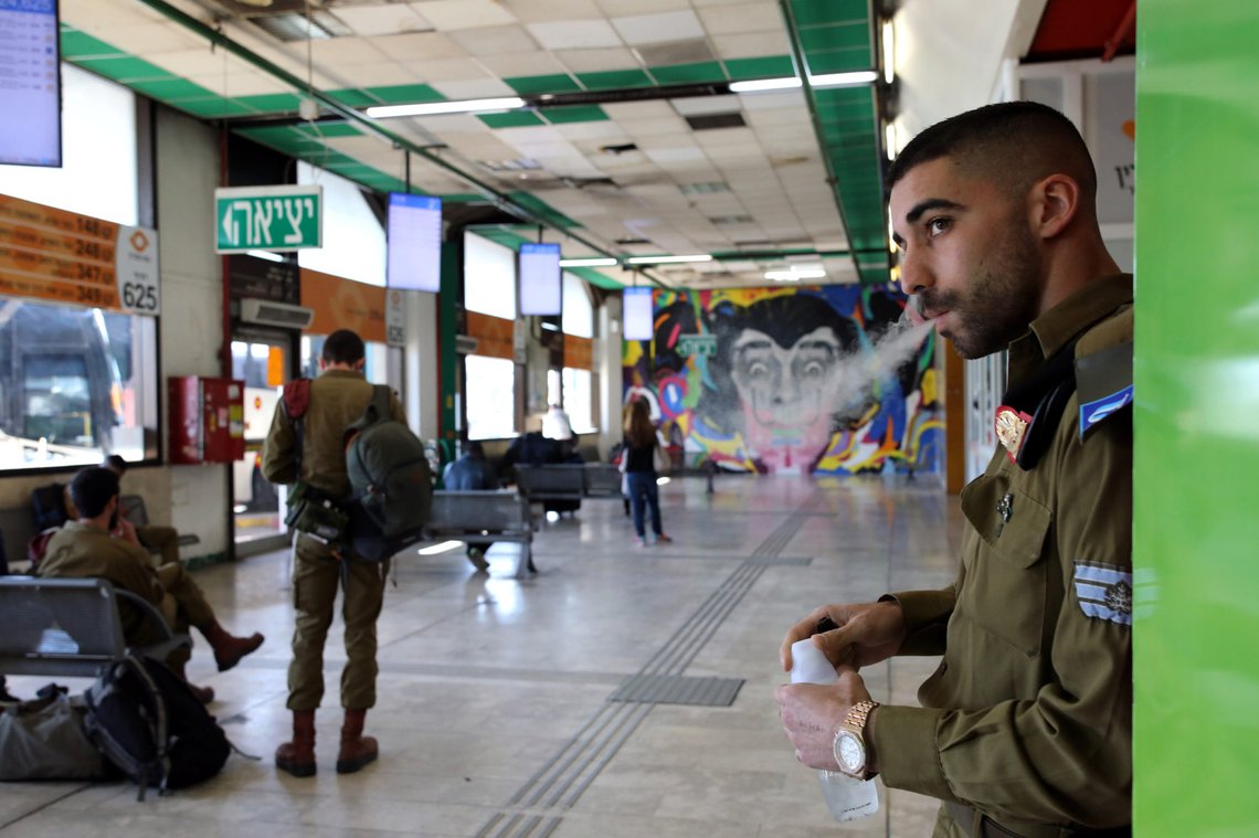 An Israeli soldier smokes as he waits with others to board buses at a terminal at the Central Bus Station in Tel Aviv, Israel, February 3, 2019. REUTERS/Corinna Kern SEARCH "ISRAEL BUS" FOR THIS STORY. SEARCH "WIDER IMAGE" FOR ALL STORIES. An Israeli soldier smokes as he waits with others to board buses at a terminal at the Central Bus Station in Tel Aviv, Israel, February 3, 2019. REUTERS/Corinna Kern SEARCH "ISRAEL BUS" FOR THIS STORY. SEARCH "WIDER IMAGE" FOR ALL STORIES.
