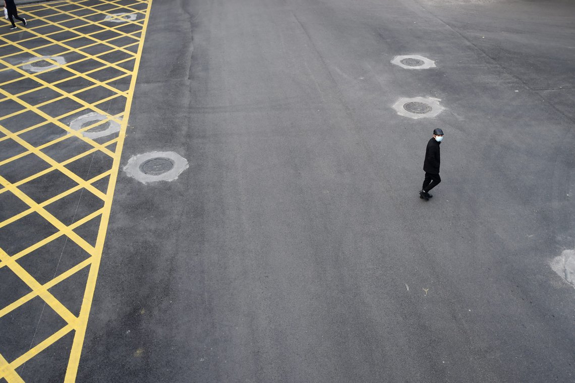 A man wearing a face mask crosses a road in Wuhan, the epicentre of the novel coronavirus outbreak, Hubei province, China February 24, 2020. REUTERS/Stringer CHINA OUT. A man wearing a face mask crosses a road in Wuhan, the epicentre of the novel coronavirus outbreak, Hubei province, China February 24, 2020. REUTERS/Stringer CHINA OUT.