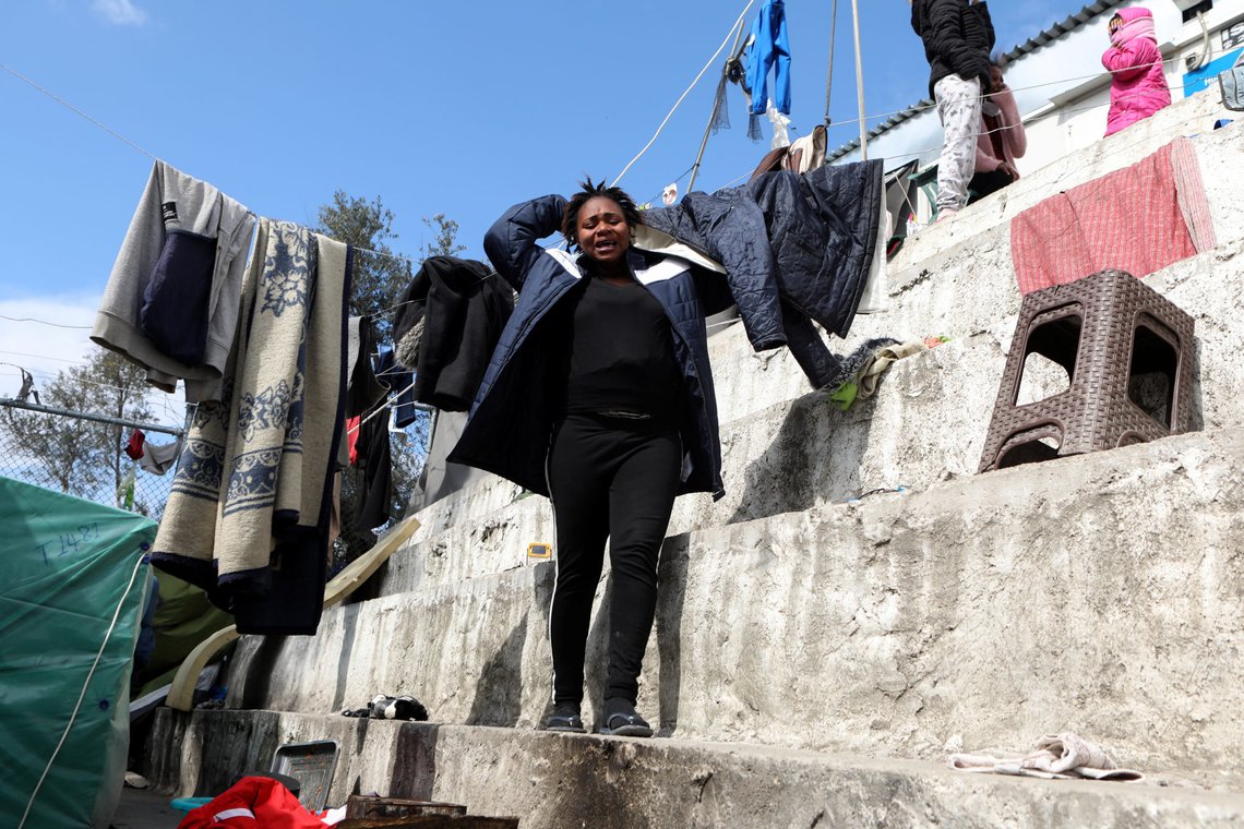 A woman reacts as a fire burns containers used to house refugees and migrants in the Moria camp on the island of Lesbos, Greece, March 16, 2020. REUTERS/Elias Marcou A woman reacts as a fire burns containers used to house refugees and migrants in the Moria camp on the island of Lesbos, Greece, March 16, 2020. REUTERS/Elias Marcou