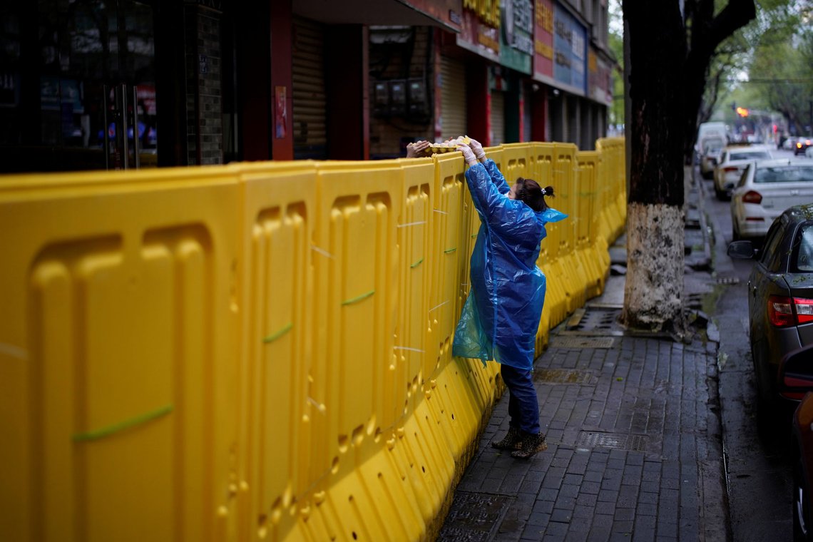 A woman wearing a face mask passes eggs above the barriers, which have been built to block buildings from a street in Wuhan, Hubei province, the epicenter of China's coronavirus disease (COVID-19) outbreak, March 29, 2020. REUTERS/Aly Song A woman wearing a face mask passes eggs above the barriers, which have been built to block buildings from a street in Wuhan, Hubei province, the epicenter of China's coronavirus disease (COVID-19) outbreak, March 29, 2020. REUTERS/Aly Song