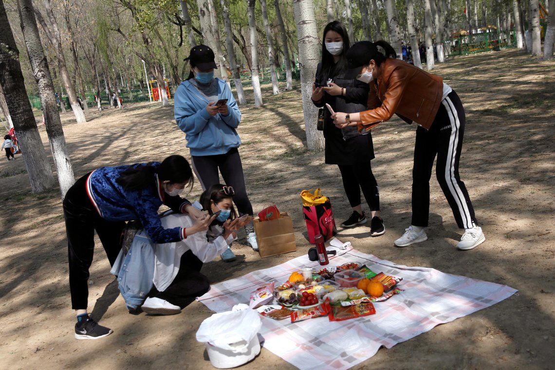 Women wearing face masks take pictures of their picnic food after they arranged them on a sheet at a park during Chinese Qingming festival holiday in Beijing, as the spread of the novel coronavirus disease (COVID-19) continues in the country, China April 6, 2020. REUTERS/Tingshu Wang Women wearing face masks take pictures of their picnic food after they arranged them on a sheet at a park during Chinese Qingming festival holiday in Beijing, as the spread of the novel coronavirus disease (COVID-19) continues in the country, China April 6, 2020. REUTERS/Tingshu Wang