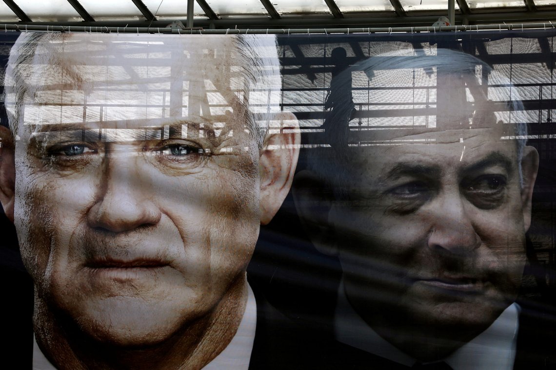 FILE PHOTO: A banner depicts Benny Gantz, leader of Blue and White party, and Israel Prime minister Benjamin Netanyahu, as part of Blue and White party's campaign ahead of the upcoming election, in Tel Aviv, Israel February 17, 2020. REUTERS/Ammar Awad/File Photo FILE PHOTO: A banner depicts Benny Gantz, leader of Blue and White party, and Israel Prime minister Benjamin Netanyahu, as part of Blue and White party's campaign ahead of the upcoming election, in Tel Aviv, Israel February 17, 2020. REUTERS/Ammar Awad/File Photo