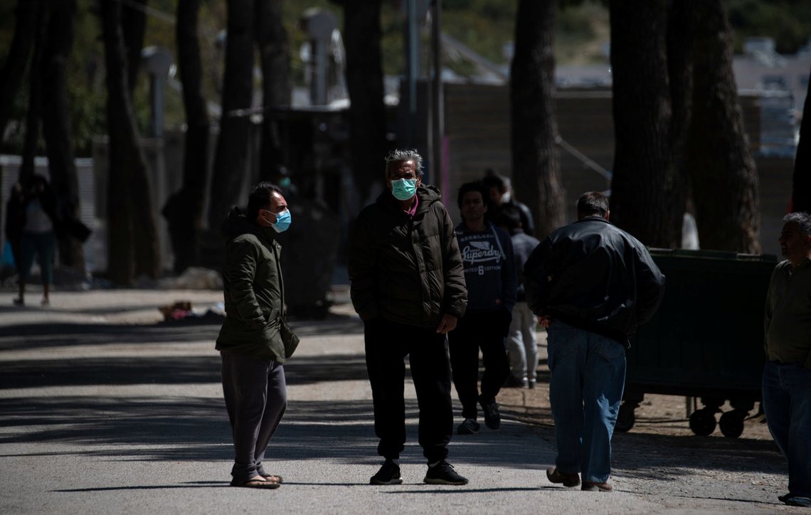 Migrants wearing protective face masks stand at the entrance of the Ritsona camp, after authorities found 20 coronavirus cases and placed the camp under quarantine, following the outbreak of coronavirus disease (COVID-19), in Ritsona, Greece, April 2, 2020. REUTERS/Alkis Konstantinidis Migrants wearing protective face masks stand at the entrance of the Ritsona camp, after authorities found 20 coronavirus cases and placed the camp under quarantine, following the outbreak of coronavirus disease (COVID-19), in Ritsona, Greece, April 2, 2020. REUTERS/Alkis Konstantinidis