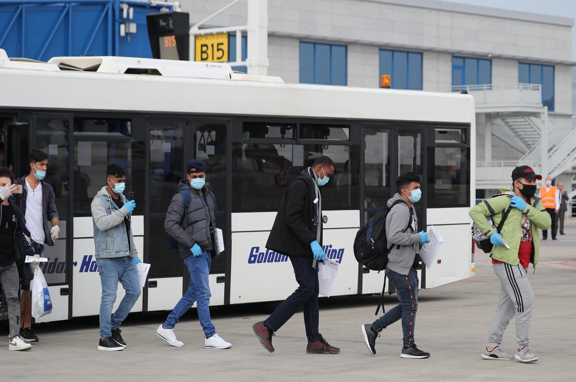 Refugees and migrants from overcrowded migrant camps who will be transferred to Britain where they will reunite with their families, wear protective face masks as a precaution against the coronavirus disease (COVID-19) as they walk to board their flight at the Athens International Airport, Greece, May 11, 2020. REUTERS/Alkis Konstantinidis Refugees and migrants from overcrowded migrant camps who will be transferred to Britain where they will reunite with their families, wear protective face masks as a precaution against the coronavirus disease (COVID-19) as they walk to board their flight at the Athens International Airport, Greece, May 11, 2020. REUTERS/Alkis Konstantinidis