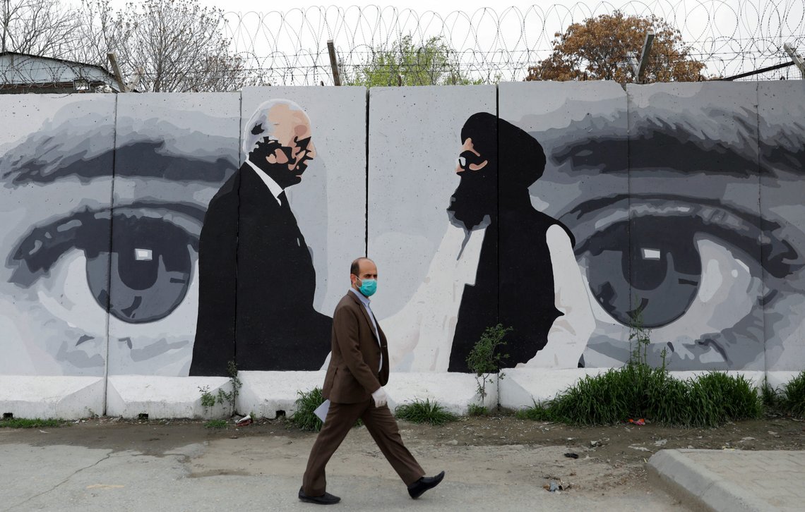 FILE PHOTO: An Afghan man wearing a protective face mask walks past a wall painted with photo of Zalmay Khalilzad, U.S. envoy for peace in Afghanistan, and Mullah Abdul Ghani Baradar, the leader of the Taliban delegation, in Kabul, Afghanistan April 13, 2020.REUTERS/Mohammad Ismail/File Photo FILE PHOTO: An Afghan man wearing a protective face mask walks past a wall painted with photo of Zalmay Khalilzad, U.S. envoy for peace in Afghanistan, and Mullah Abdul Ghani Baradar, the leader of the Taliban delegation, in Kabul, Afghanistan April 13, 2020.REUTERS/Mohammad Ismail/File Photo