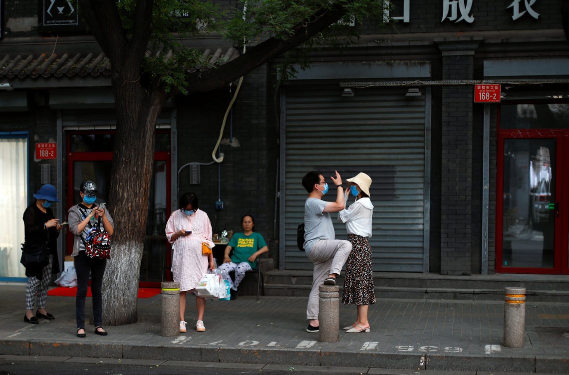 People wearing protective masks wait for the bus, after a new outbreak of the coronavirus disease (COVID-19), in an old area of Beijing, China, June 23, 2020. REUTERS/Thomas Peter People wearing protective masks wait for the bus, after a new outbreak of the coronavirus disease (COVID-19), in an old area of Beijing, China, June 23, 2020. REUTERS/Thomas Peter