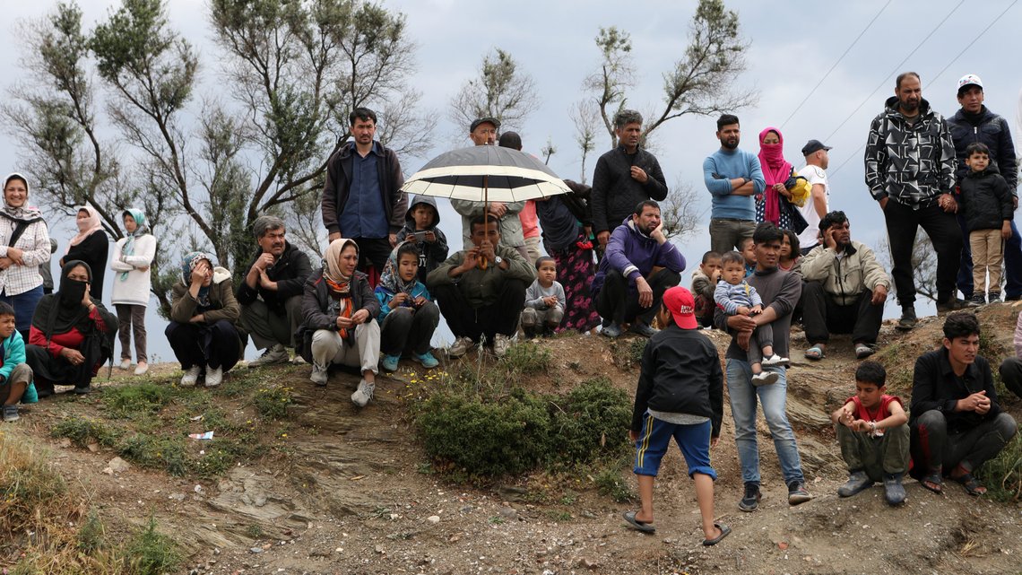 Migrants from the Moria camp watch other migrants boarding busses to the port, from where they will be transferred to the mainland as a precaution against the spread of the coronavirus disease (COVID-19) outbreak, on the island of Lesbos, Greece, May 3, 2020. REUTERS/Elias Marcou TPX IMAGES OF THE DAY Migrants from the Moria camp watch other migrants boarding busses to the port, from where they will be transferred to the mainland as a precaution against the spread of the coronavirus disease (COVID-19) outbreak, on the island of Lesbos, Greece, May 3, 2020. REUTERS/Elias Marcou TPX IMAGES OF THE DAY