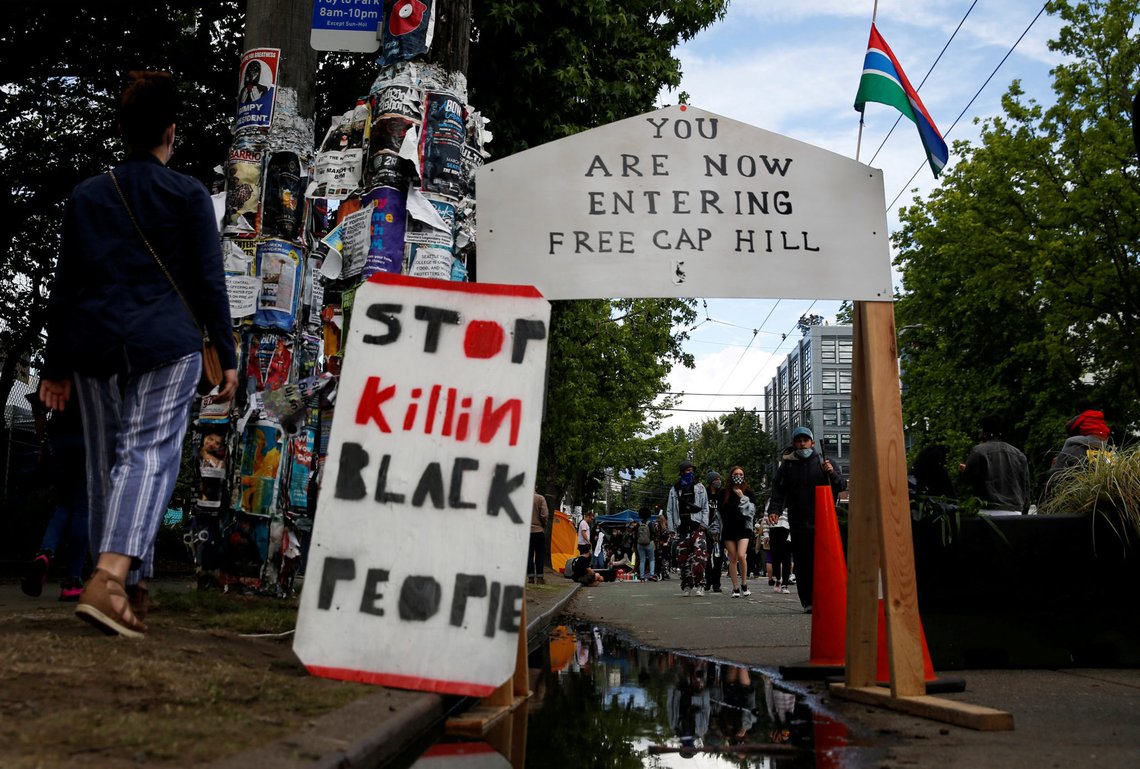 FILE PHOTO: People walk by signs at a barrier set up at the edge of the self-proclaimed CHAZ/CHOP zone around the Seattle Police Department's East Precinct as people call for the defunding of police and protest against racial inequality in the aftermath of the death in Minneapolis police custody of George Floyd, in Seattle, Washington, U.S. June 14, 2020. REUTERS/Lindsey Wasson/File Photo FILE PHOTO: People walk by signs at a barrier set up at the edge of the self-proclaimed CHAZ/CHOP zone around the Seattle Police Department's East Precinct as people call for the defunding of police and protest against racial inequality in the aftermath of the death in Minneapolis police custody of George Floyd, in Seattle, Washington, U.S. June 14, 2020. REUTERS/Lindsey Wasson/File Photo