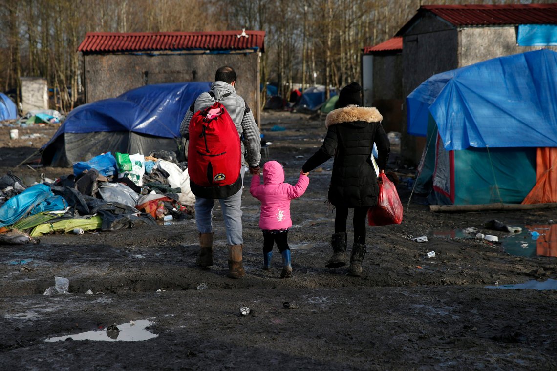 Migrants walks past shelters in a muddy field called the Grande-Synthe jungle, near Dunkirk, northern France, January 12, 2016. The Grande-Synthe jungle is a camp of tents and makeshift shelters where migrants and asylum seekers from Irak, Kurdistan and Syria gather. REUTERS/Benoit Tessier Migrants walks past shelters in a muddy field called the Grande-Synthe jungle, near Dunkirk, northern France, January 12, 2016. The Grande-Synthe jungle is a camp of tents and makeshift shelters where migrants and asylum seekers from Irak, Kurdistan and Syria gather. REUTERS/Benoit Tessier