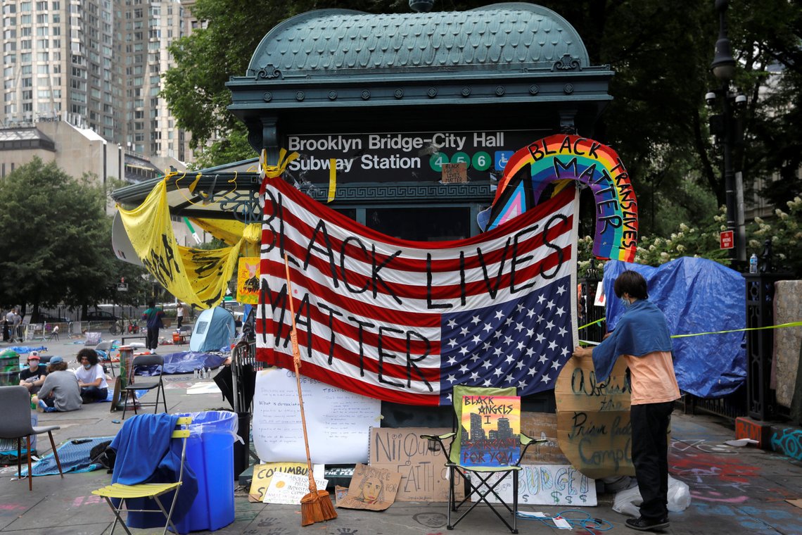 A demonstrator adjusts signs in an area being called the "City Hall Autonomous Zone" that has been established to protest the New York Police Department (NYPD) and in support of "Black Lives Matter" near City Hall in lower Manhattan, in New York City, U.S., July 1, 2020. REUTERS/Mike Segar A demonstrator adjusts signs in an area being called the "City Hall Autonomous Zone" that has been established to protest the New York Police Department (NYPD) and in support of "Black Lives Matter" near City Hall in lower Manhattan, in New York City, U.S., July 1, 2020. REUTERS/Mike Segar