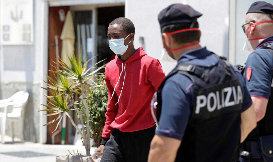 A migrant man wearing a protective mask walks past police officers, after getting off an Italian ferry Moby Zaza, where he was quarantined and identified by the police officers, in Sicily, Italy July 6, 2020. REUTERS/Antonio Parrinello A migrant man wearing a protective mask walks past police officers, after getting off an Italian ferry Moby Zaza, where he was quarantined and identified by the police officers, in Sicily, Italy July 6, 2020. REUTERS/Antonio Parrinello