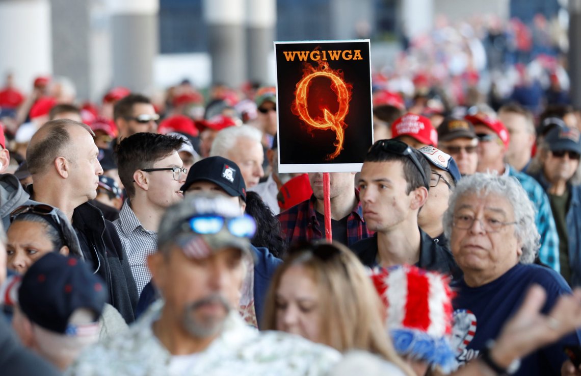 A man in the crowd holds a QAnon sign with the group's abbreviation of their rallying cry "Where we go one, we go all" as crowds gather to attend U.S. President Donald Trump's campaign rally at the Las Vegas Convention Center in Las Vegas, Nevada, U.S., February 21, 2020. REUTERS/Patrick Fallon A man in the crowd holds a QAnon sign with the group's abbreviation of their rallying cry "Where we go one, we go all" as crowds gather to attend U.S. President Donald Trump's campaign rally at the Las Vegas Convention Center in Las Vegas, Nevada, U.S., February 21, 2020. REUTERS/Patrick Fallon