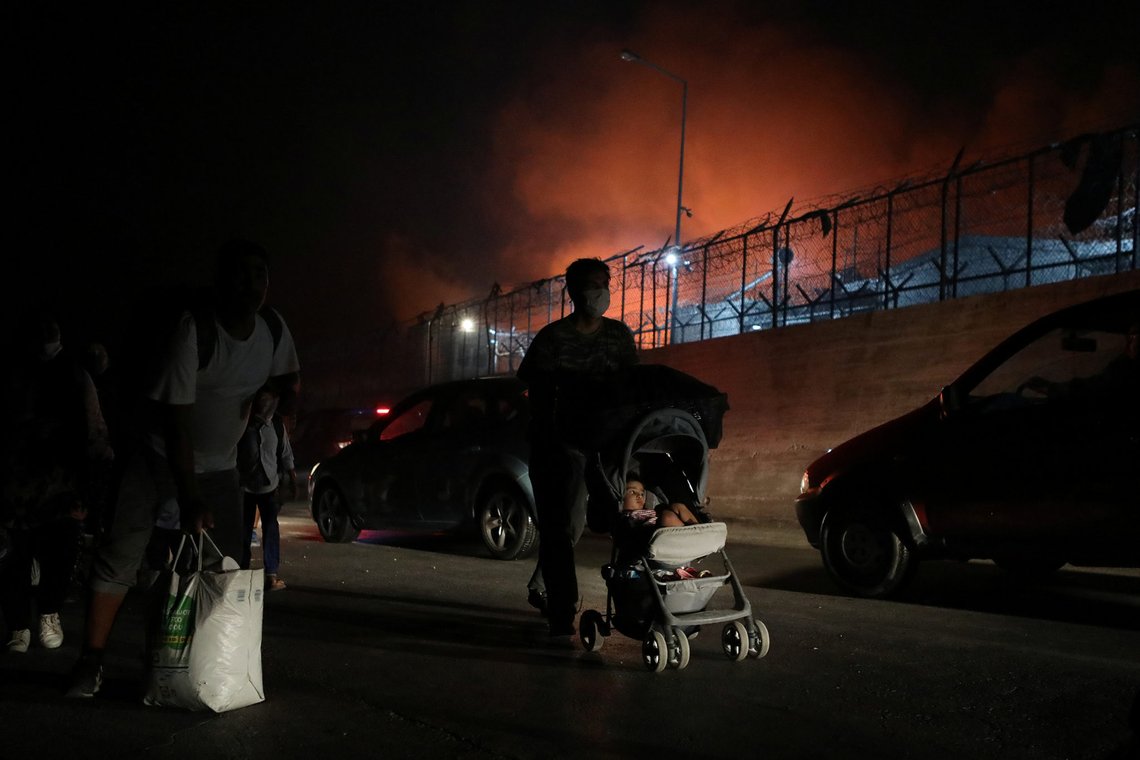 Refugees and migrants carry their belongings as they flee a fire burning at the Moria camp on the island of Lesbos, Greece, September 9, 2020. REUTERS/Elias Marcou Refugees and migrants carry their belongings as they flee a fire burning at the Moria camp on the island of Lesbos, Greece, September 9, 2020. REUTERS/Elias Marcou