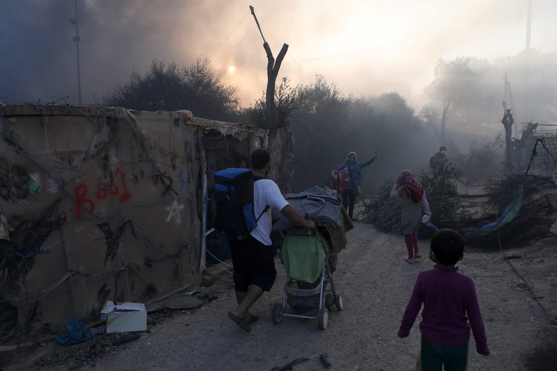 Refugees and migrants carry their belongings as they flee a fire burning at the Moria camp on the island of Lesbos, Greece, September 9, 2020. REUTERS/Elias Marcou Refugees and migrants carry their belongings as they flee a fire burning at the Moria camp on the island of Lesbos, Greece, September 9, 2020. REUTERS/Elias Marcou