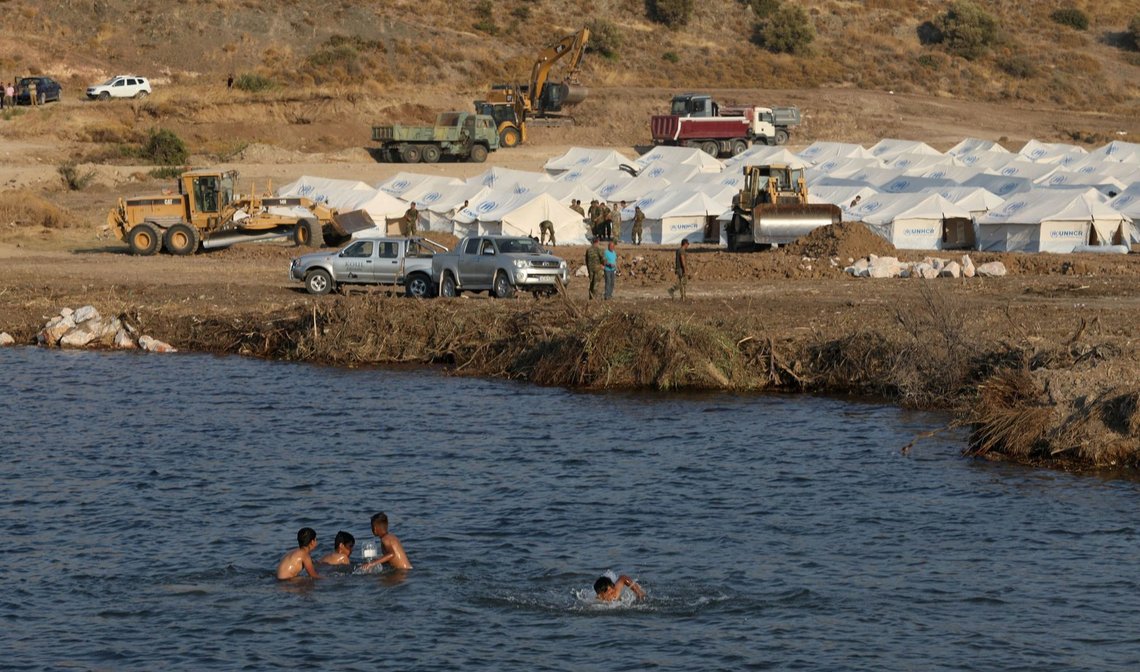 Migrants swim next to a new temporary camp where refugees and migrants from the destroyed Moria camp will be accommodated, on the island of Lesbos, Greece, September 12, 2020. REUTERS/Elias Marcou Migrants swim next to a new temporary camp where refugees and migrants from the destroyed Moria camp will be accommodated, on the island of Lesbos, Greece, September 12, 2020. REUTERS/Elias Marcou