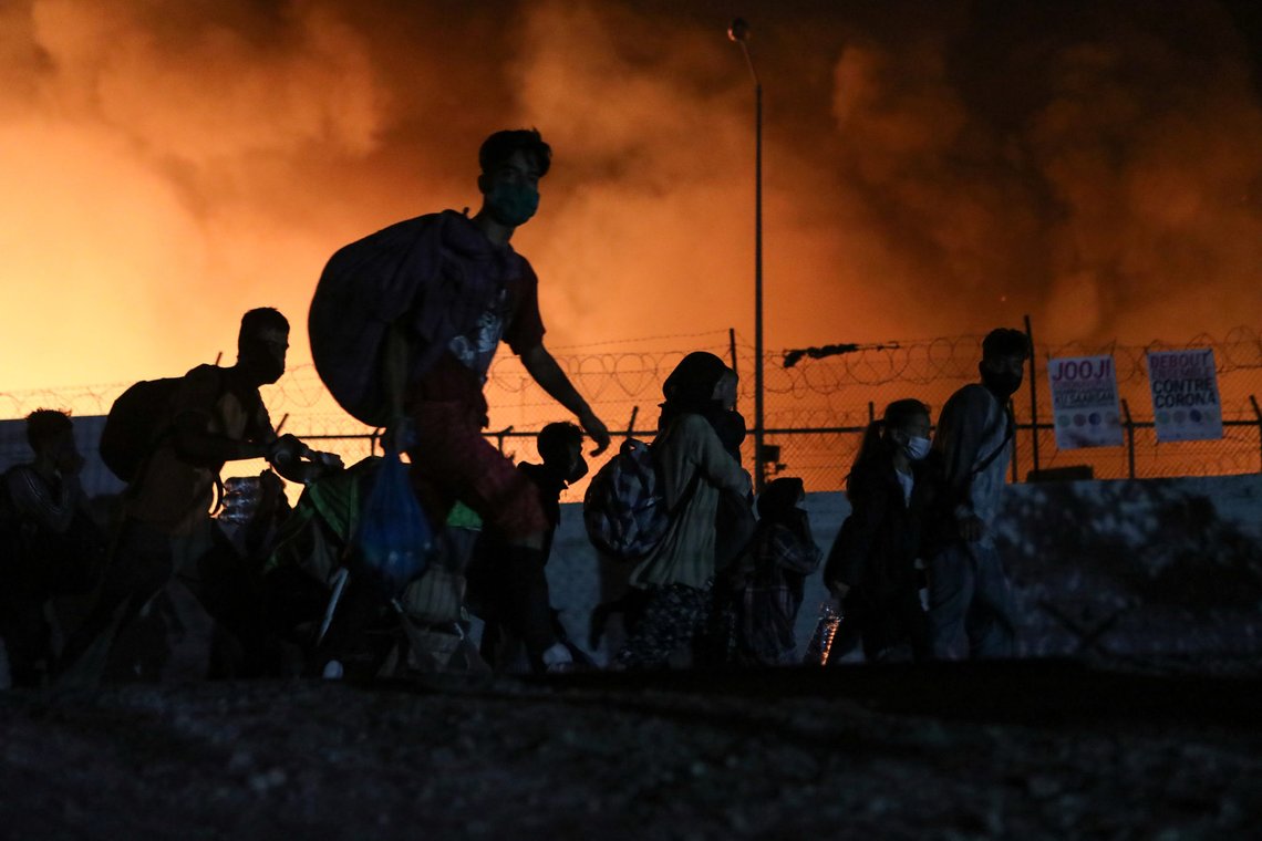 Refugees and migrants carry their belongings as they flee from a fire burning at the Moria camp, on the island of Lesbos, Greece, September 9, 2020. REUTERS/Elias Marcou Refugees and migrants carry their belongings as they flee from a fire burning at the Moria camp, on the island of Lesbos, Greece, September 9, 2020. REUTERS/Elias Marcou