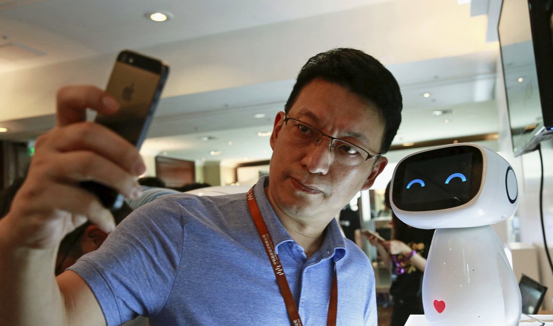 A visitor takes a selfie with Baidu's robot Xiaodu at the 2015 Baidu World Conference in Beijing, China, September 8, 2015. Xiaodu, an artificial intelligent robot developed by Baidu, has access to the company's search engine database and can respond to voice commands, Baidu says.REUTERS/Kim Kyung-Hoon A visitor takes a selfie with Baidu's robot Xiaodu at the 2015 Baidu World Conference in Beijing, China, September 8, 2015. Xiaodu, an artificial intelligent robot developed by Baidu, has access to the company's search engine database and can respond to voice commands, Baidu says.REUTERS/Kim Kyung-Hoon