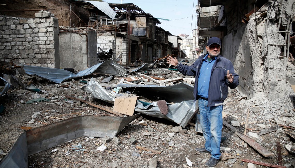 Eduard Chechyan gestures in the yard of his apartment building, destroyed by shelling by Azerbaijan's artillery, during a military conflict in Stepanakert, the separatist region of Nagorno-Karabakh, Saturday, Oct. 10, 2020. Armenia and Azerbaijan have agreed to a Russia-brokered cease-fire in Nagorno-Karabakh after two weeks of heavy fighting that marked the worst outbreak of hostilities in the separatist region in more than a quarter-century. (AP Photo) Eduard Chechyan gestures in the yard of his apartment building, destroyed by shelling by Azerbaijan's artillery, during a military conflict in Stepanakert, the separatist region of Nagorno-Karabakh, Saturday, Oct. 10, 2020. Armenia and Azerbaijan have agreed to a Russia-brokered cease-fire in Nagorno-Karabakh after two weeks of heavy fighting that marked the worst outbreak of hostilities in the separatist region in more than a quarter-century. (AP Photo)