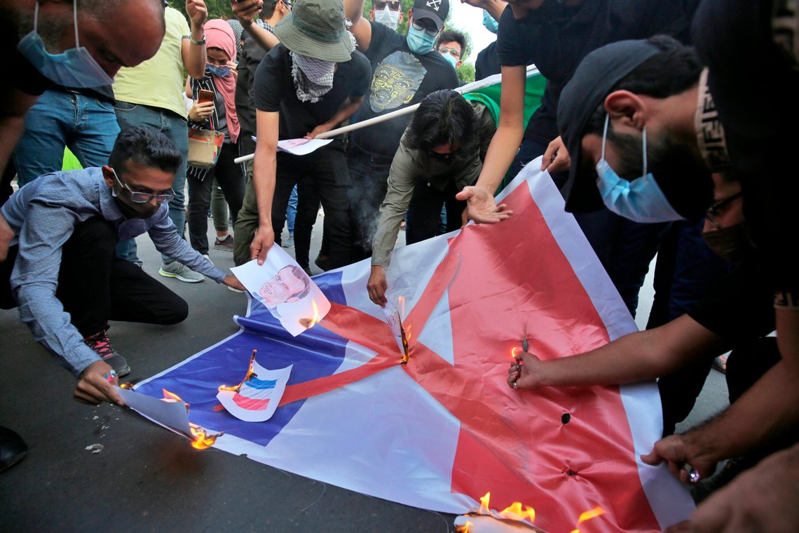 Protesters burn a representation of the French flag and pictures of the French president during a protest over caricatures of the Prophet Muhammad they deem insulting and blasphemous in Baghdad, Iraq, Monday, Oct. 26, 2020. Muslims in the Middle East and beyond on Monday called for boycotts of French products and for protests over the caricatures, but France's president has vowed his country will not back down from its secular ideals and defense of free speech. (AP Photo/Khalid Mohammed) Protesters burn a representation of the French flag and pictures of the French president during a protest over caricatures of the Prophet Muhammad they deem insulting and blasphemous in Baghdad, Iraq, Monday, Oct. 26, 2020. Muslims in the Middle East and beyond on Monday called for boycotts of French products and for protests over the caricatures, but France's president has vowed his country will not back down from its secular ideals and defense of free speech. (AP Photo/Khalid Mohammed)