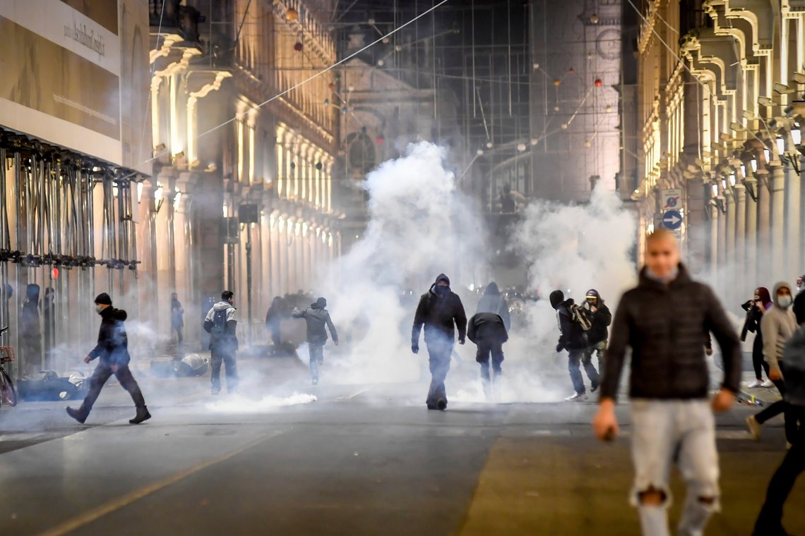 Smoke billows as clashes broke out during a protest against the government restriction measures to curb the spread of COVID-19 in Turin, Italy, Monday, Oct. 26, 2020. Protesters turned out by the hundreds in Italian several cities and towns on Monday to vent anger, sometimes violently, over the latest anti-COVID-19 rules, which force restaurants and cafes to close early, shutter cinema, gyms and other leisure venues. In the northern city of Turin, demonstrators broke off from a peaceful protest and hurled smoke bombs and bottles at police in the city square where the Piedmont regional government is headquartered. (Claudio Furlan/LaPresse via AP) Smoke billows as clashes broke out during a protest against the government restriction measures to curb the spread of COVID-19 in Turin, Italy, Monday, Oct. 26, 2020. Protesters turned out by the hundreds in Italian several cities and towns on Monday to vent anger, sometimes violently, over the latest anti-COVID-19 rules, which force restaurants and cafes to close early, shutter cinema, gyms and other leisure venues. In the northern city of Turin, demonstrators broke off from a peaceful protest and hurled smoke bombs and bottles at police in the city square where the Piedmont regional government is headquartered. (Claudio Furlan/LaPresse via AP)