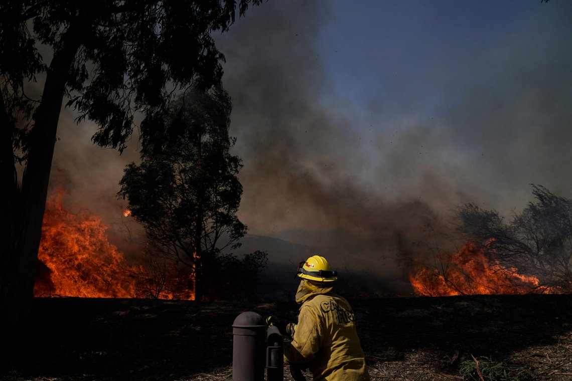 A firefighter watches flames from the Silverado Fire, Monday, Oct. 26, 2020, in Irvine, Calif. A fast-moving wildfire forced evacuation orders for 60,000 people in Southern California on Monday as powerful winds across the state prompted power to be cut to hundreds of thousands to prevent utility equipment from sparking new blazes. (AP Photo/Jae C. Hong) A firefighter watches flames from the Silverado Fire, Monday, Oct. 26, 2020, in Irvine, Calif. A fast-moving wildfire forced evacuation orders for 60,000 people in Southern California on Monday as powerful winds across the state prompted power to be cut to hundreds of thousands to prevent utility equipment from sparking new blazes. (AP Photo/Jae C. Hong)