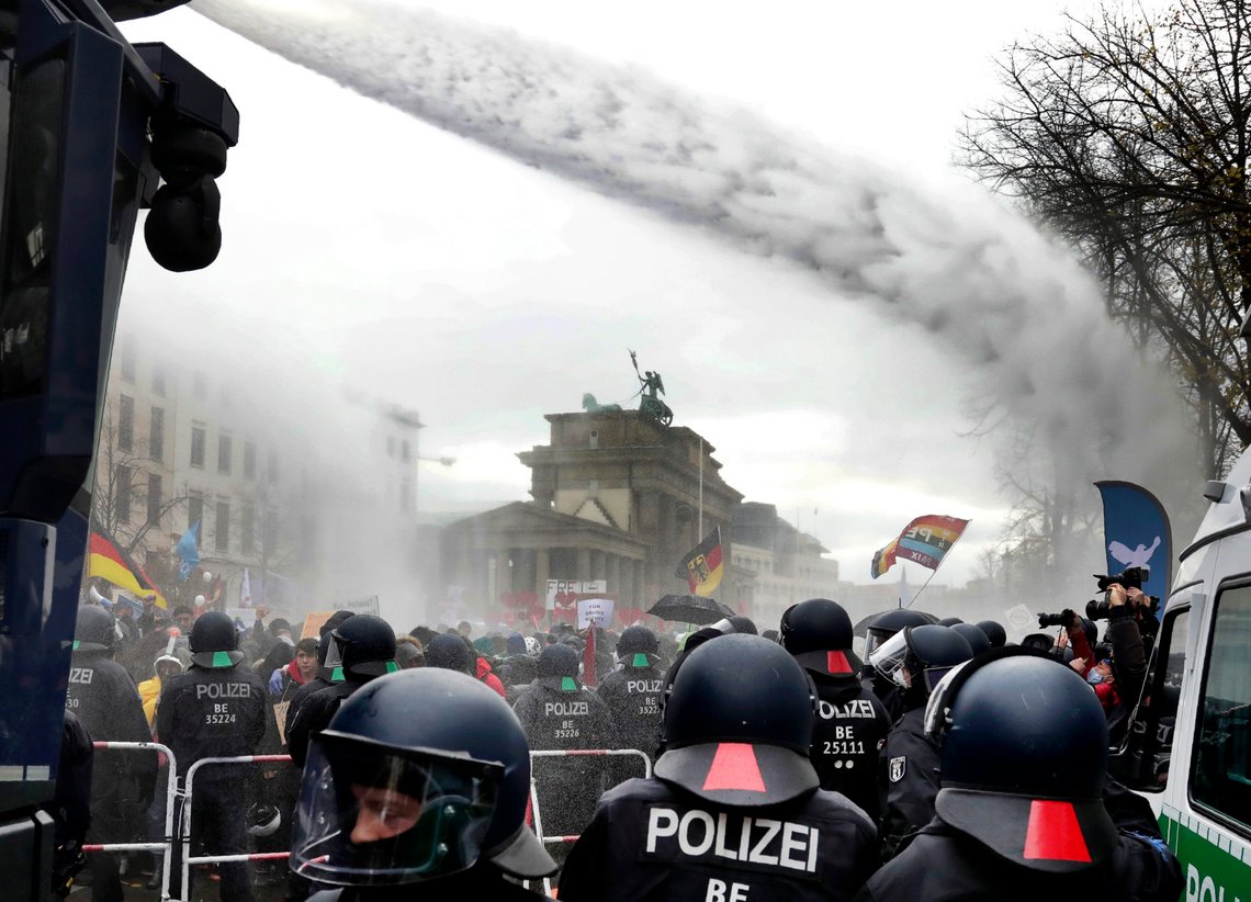 Police uses water canons to clear a blocked a road between the Brandenburg Gate and the Reichstag building, home of the German federal parliament, as people attend a protest rally in front of the Brandenburg Gate in Berlin, Germany, Wednesday, Nov. 18, 2020 against the coronavirus restrictions in Germany. Police in Berlin have requested thousands of reinforcements from other parts of Germany to cope with planned protests by people opposed to coronavirus restrictions. (AP Photo/Michael Sohn) Police uses water canons to clear a blocked a road between the Brandenburg Gate and the Reichstag building, home of the German federal parliament, as people attend a protest rally in front of the Brandenburg Gate in Berlin, Germany, Wednesday, Nov. 18, 2020 against the coronavirus restrictions in Germany. Police in Berlin have requested thousands of reinforcements from other parts of Germany to cope with planned protests by people opposed to coronavirus restrictions. (AP Photo/Michael Sohn)
