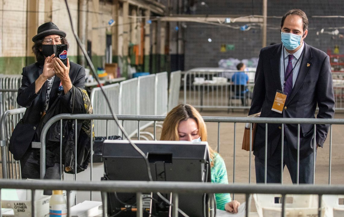 Election observers watch Jessica Lehman as she processes ballots as part of the Allegheny County Return Board's counting of the remaining absentee and mail-in ballots on Friday, Nov. 6, 2020, in Pittsburgh. (Andrew Rush /Pittsburgh Post-Gazette via AP) Election observers watch Jessica Lehman as she processes ballots as part of the Allegheny County Return Board's counting of the remaining absentee and mail-in ballots on Friday, Nov. 6, 2020, in Pittsburgh. (Andrew Rush /Pittsburgh Post-Gazette via AP)