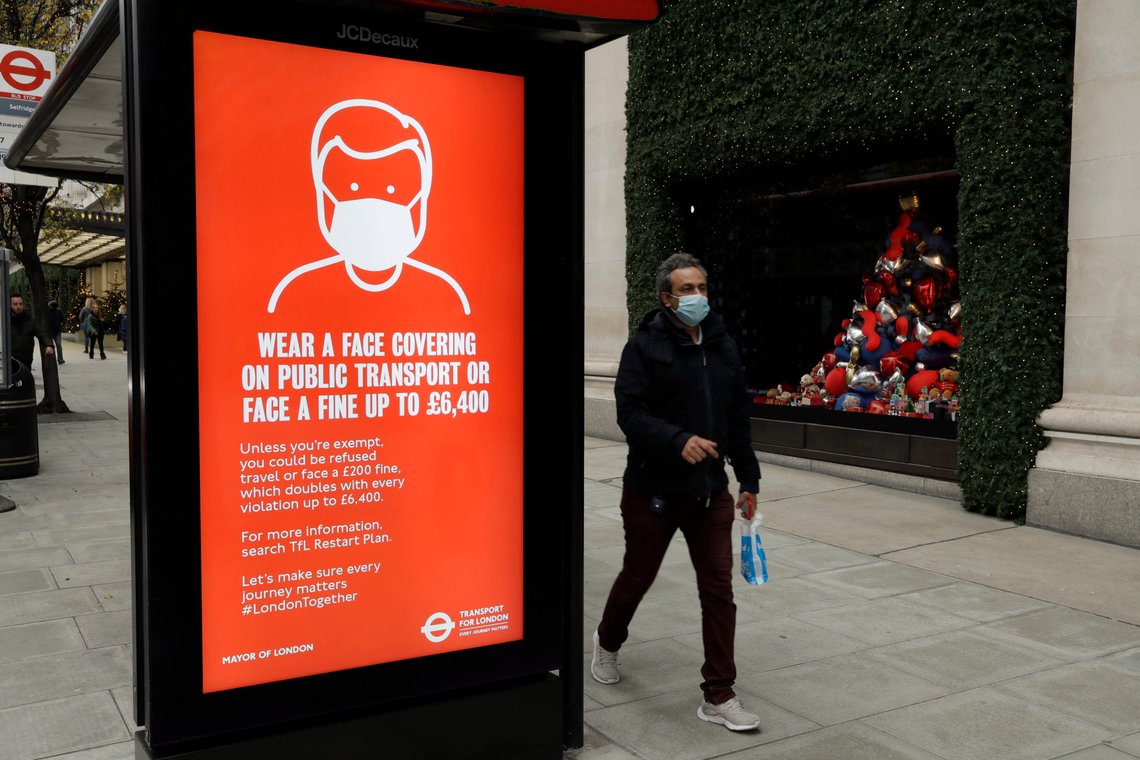 A person wearing a face mask walks past a sign on a bus stop warning people to wear a face covering on public transport or face a fine, outside the Selfridges department store on Oxford Street during England's second coronavirus lockdown, in London, Monday, Nov. 23, 2020. British Prime Minister Boris Johnson has announced plans for strict regional measures to combat COVID-19 after England's second lockdown ends Dec. 2, sparking a rebellion by members of his own party who say the move may do more harm than good. (AP Photo/Matt Dunham) A person wearing a face mask walks past a sign on a bus stop warning people to wear a face covering on public transport or face a fine, outside the Selfridges department store on Oxford Street during England's second coronavirus lockdown, in London, Monday, Nov. 23, 2020. British Prime Minister Boris Johnson has announced plans for strict regional measures to combat COVID-19 after England's second lockdown ends Dec. 2, sparking a rebellion by members of his own party who say the move may do more harm than good. (AP Photo/Matt Dunham)